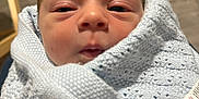 Ronnie joined the competition — help win amazing prizes! baby, newborn, infant, wrapped, blanket, blue_blanket, closeup, face, sleepy, indoors, soft_texture, knitted, bundle, cute, person, human, small, head, skin, expression
