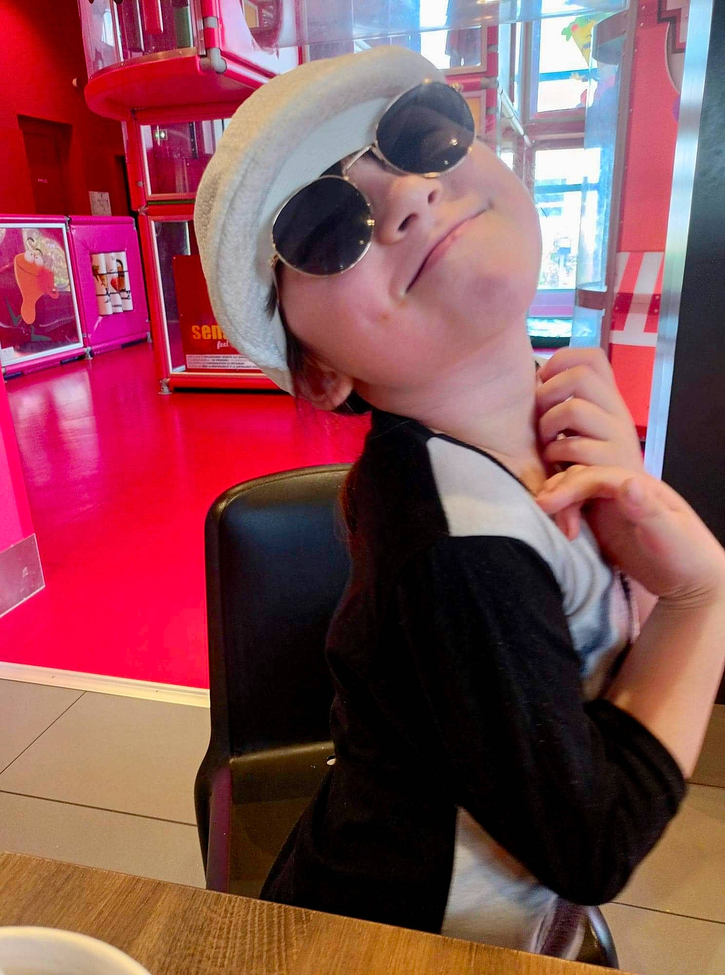 Cristal participe au concours pour gagner de l'argent avec cette photo : cap, chair, chest, comfort, elbow, eyewear, gesture, headwear, human_leg, joint, knee, leisure, person, sitting, sportswear, sunglasses, table, tableware, thigh, trunk