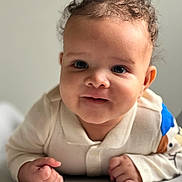 Noah a rejoint le concours — aidez-le/la à gagner de superbes lots ! baby, child, curly_hair, face, hands, light_skin, blue_eyes, clothing, long_sleeves, infant, portrait, propped_up, indoor, cute, closeup, expression, smile, young_child, soft_lighting, white_background