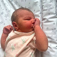 Elsie-Jay is registered to the contest to win money with this photo: newborn, baby, infant, sleeping, thumb_sucking, onesie, floral_pattern, blanket, stars, soft_light, cute, peaceful, skin, face, hand, lying_down, portrait, child, indoors, cozy