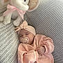baby, sleeping, pacifier, headband, pink_clothing, plush_elephant, ribbon, knitted_blanket, soft_texture, cozy, infant, cute, peaceful, indoors, child, resting, toddler, fabric, portrait, adorable