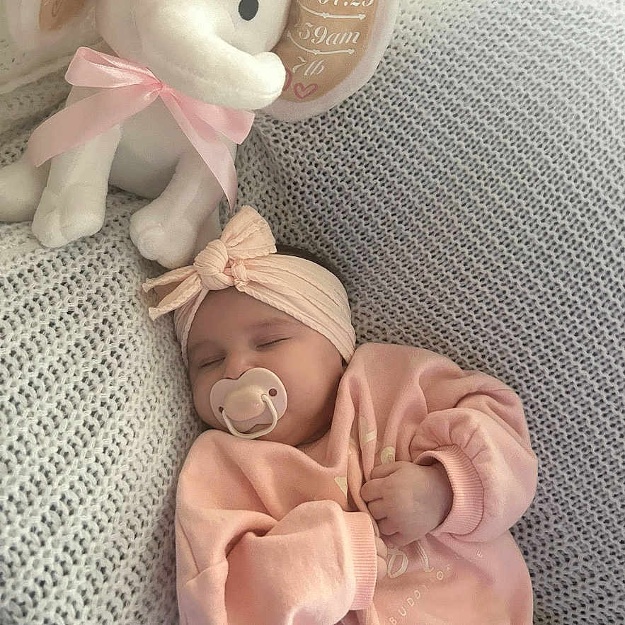 Elsie-Jay joined the competition — help win amazing prizes! adorable, baby, child, cozy, cute, fabric, headband, indoors, infant, knitted_blanket, pacifier, peaceful, pink_clothing, plush_elephant, portrait, resting, ribbon, sleeping, soft_texture, toddler