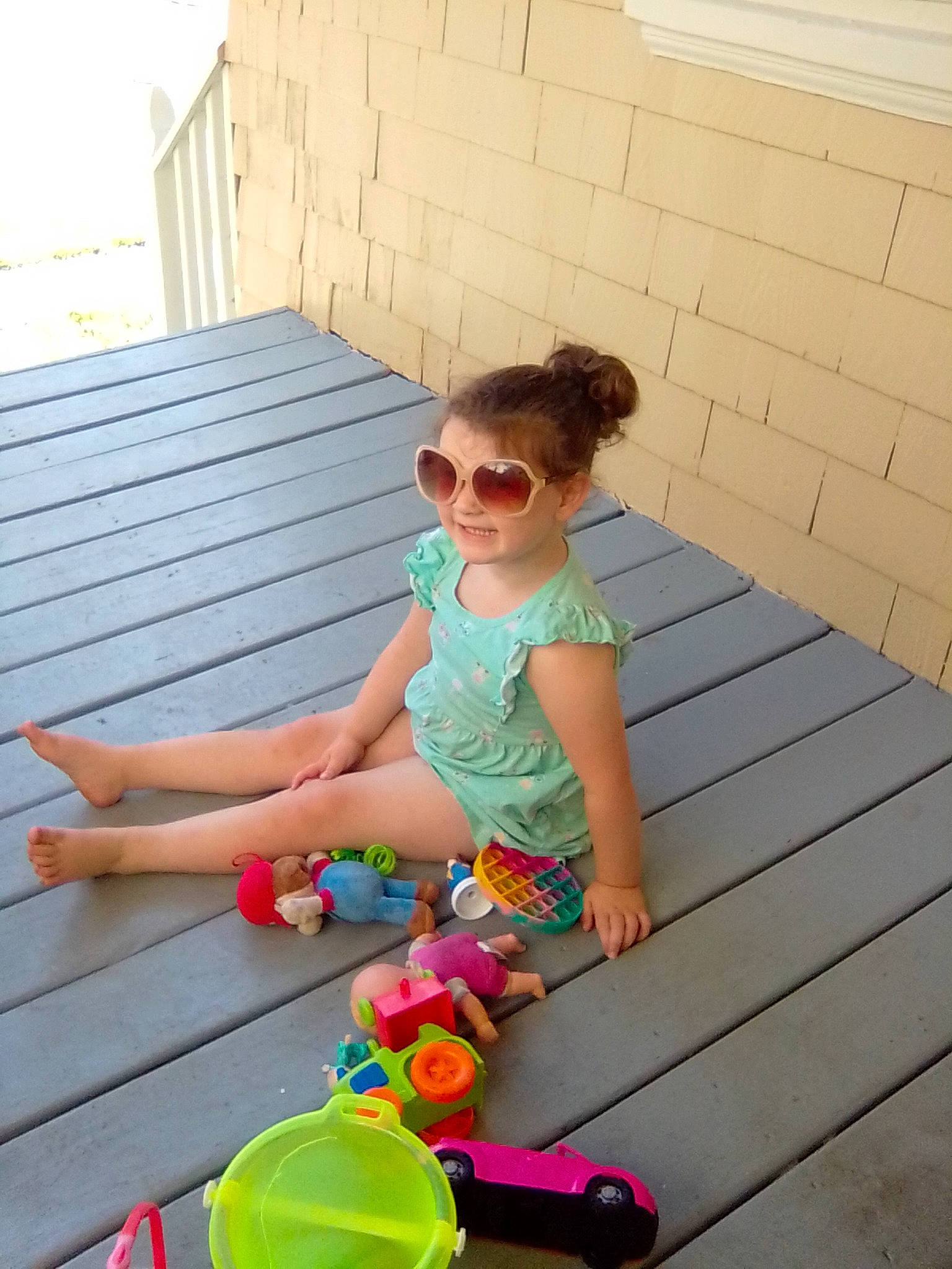 Lillie is registered to the contest to win money with this photo: baby_toddler_clothing, child, electric_blue, eyewear, flooring, fun, glasses, goggles, grass, green, hardwood, leisure, morning, person, pink, sitting, summer, sunglasses, thigh, toddler