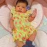 baby, infant, child, portrait, lying_down, smiling, face, eyes, hair, watermelon_pattern, green_outfit, pink_blanket, plush_toy, stuffed_animal, flower, wrist_bracelet, nursery, indoor, soft_bedding, cute