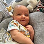 baby, infant, smile, onesie, animal_print, blanket, plush_toy, cushion, soft_toys, closeup, indoors, child, cute, relaxed, portrait, baby_clothing, happy, person, young_child, cozy
