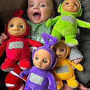 Luchi joined the competition — help win amazing prizes! baby, smiling, laughing, plush_toy, teletubby, red, green, purple, yellow, couch, striped_pants, child, indoor, happy, toy, person, fabric, hand, foot, smartphone