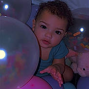 Atyra joined the competition — help win amazing prizes! child, toddler, balloons, curly_hair, plush_toy, indoor, colorful, pastel_colors, baby, cute, expression, portrait, soft_lighting, playful, person, celebration, party, close_up, smiling, curiosity