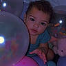 child, toddler, balloons, curly_hair, plush_toy, indoor, colorful, pastel_colors, baby, cute, expression, portrait, soft_lighting, playful, person, celebration, party, close_up, smiling, curiosity