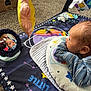 Micah is registered to the contest to win money with this photo: baby, infant, mirror, play_mat, toy, pillow, carpet, reflection, clothing, striped_sleeves, floor, curious, indoor, child, face, head, colorful, soft_toys, baby_play_area, looking