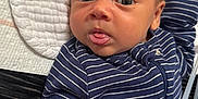 Micah is registered to the contest to win money with this photo: baby, infant, face, tongue, blue_clothing, striped_clothing, blanket, texture, closeup, skin, head, eyes, person, newborn, lying_down, cute, expression, indoor, young_child, sleepwear