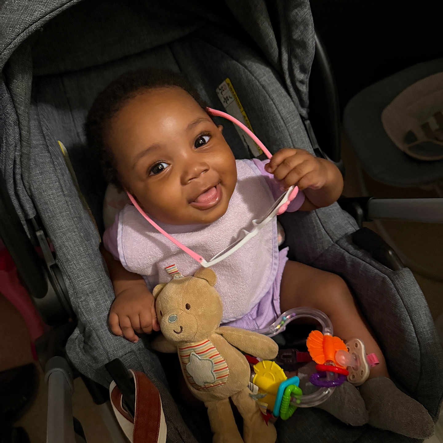 Najiah is registered to the contest to win money with this photo: accessory, baby, car_seat, child, clothing, cute, face, footwear, hand, happy, head, indoor, infant, person, playful, seat, smiling, sunglasses, teddy_bear, toy
