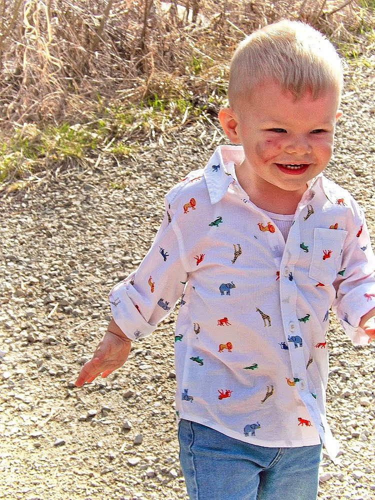 Camden is registered to the contest to win money with this photo: child, clothing, denim, facial_expression, fun, grass, happy, jeans, joy, leisure, pattern, people_in_nature, person, plant, sleeve, smile, soil, street_fashion, t_shirt, toddler