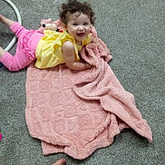 Braelynn joined the competition — help win amazing prizes! child, toddler, carpet, blanket, toy, yellow_clothing, pink_clothing, crawling, playing, indoor, curly_hair, baby_toy, floor, smiling, happy, person, cute, infant, soft_texture, colorful