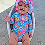 baby, child, smiling, sitting, beach, sand, sun_hat, swimsuit, colorful, floral_pattern, outdoor, happy, person, summer, vacation, cute, portrait, sunshine, relaxing, seat