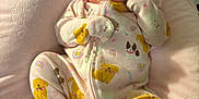 Hazel joined the competition — help win amazing prizes! baby, infant, onesie, yellow_dogs, rainbows, pink_cushion, soft_texture, sleepy, curious, cute, clothing, child, portrait, indoor, resting, newborn, small, cute_pattern, fabric, relaxed