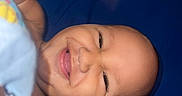 Ilyan participe au concours pour gagner de l'argent avec cette photo : baby, smile, happy, child, face, skin, hand, blue_background, lying_down, infant, closeup, person, cute, expression, teeth, indoors, young_child, portrait, joy, playful