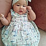 baby, infant, child, headband, bow, dress, sailboat_pattern, white_tights, pillow, couch, soft_fabric, indoors, cute, adorable, chubby_cheeks, relaxed, portrait, person, sleepwear, resting