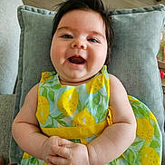 Olivia a rejoint le concours — aidez-le/la à gagner de superbes lots ! baby, smile, happy, child, dress, pattern, lemon, hands, cushion, indoor, hair, infant, person, face, skin, arm, furniture, comfort, portrait, cute