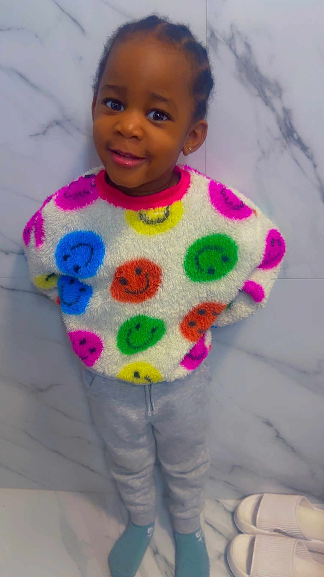 Alexis joined the competition — help win amazing prizes! child, smiling, sweater, colorful, smiley_faces, gray_sweatpants, socks, standing, marble_wall, floor, slippers, indoor, portrait, happy, young_child, cozy, casual_clothing, cute, person, fashion