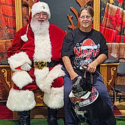 Franklin D Roosevelt joined the competition — help win amazing prizes! santa_claus, woman, dog, christmas, holiday, smiling, glasses, costume, black_dog, decorations, presents, indoor, portrait, festive, seated, leash, collar, boots, red_clothing, green_carpet