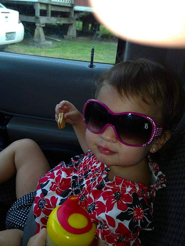 Briley is registered to the contest to win money with this photo: car, cool, eyewear, facial_expression, finger, fun, glasses, goggles, head_restraint, lip, mouth, person, pink, skin, sunglasses, thigh, toddler, vehicle_door, vision_care, white