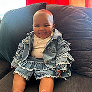 Chylyn joined the competition — help win amazing prizes! baby, barefoot, child, clothing, couch, cozy, cute, denim_jacket, denim_skirt, face, foot, happy, head, indoor, infant, person, portrait, red_curtain, sitting, smiling