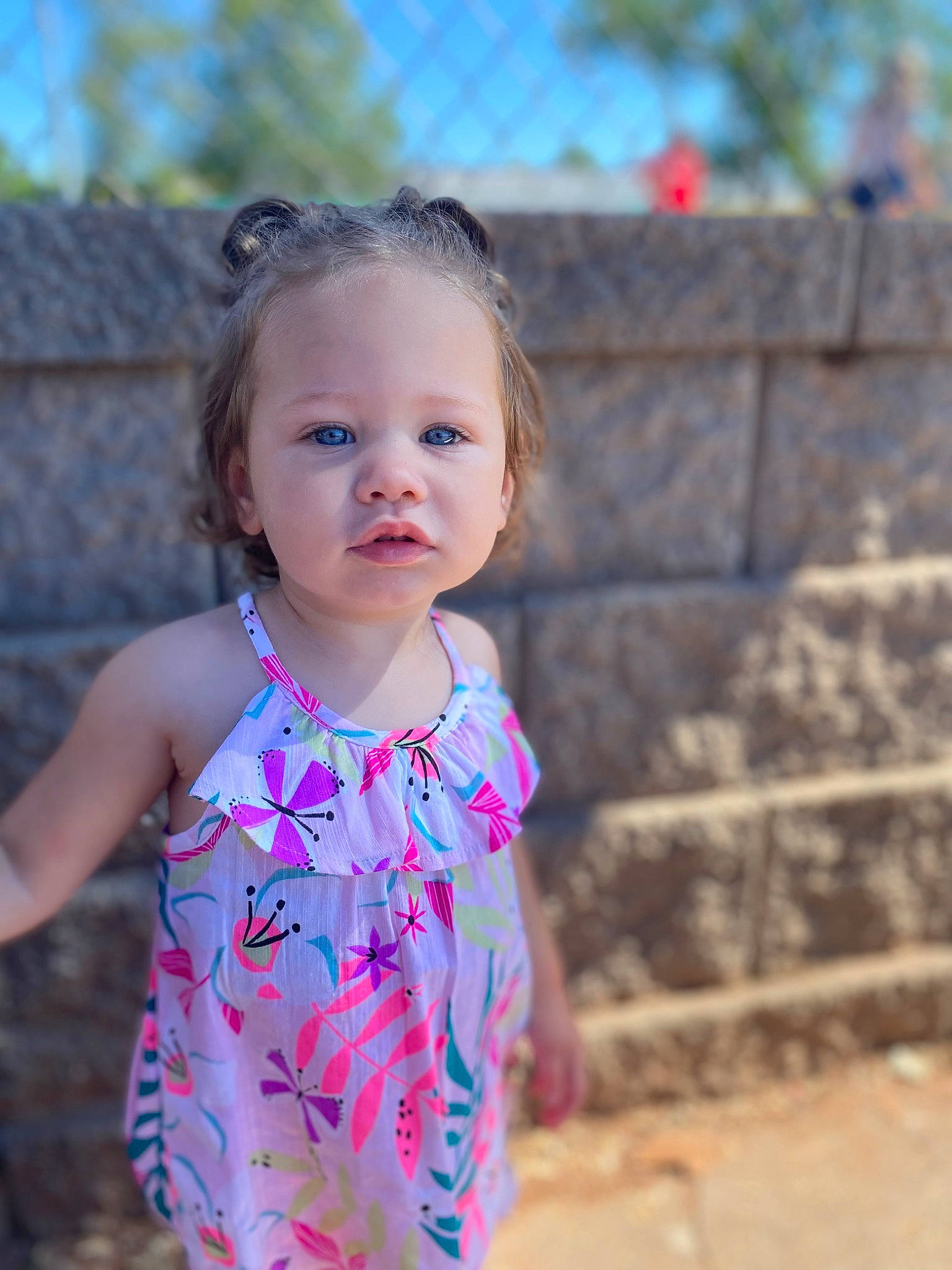 Ada is registered to the contest to win money with this photo: baby_toddler_clothing, chin, dress, eye, face, facial_expression, grass, happy, head, iris, neck, people_in_nature, person, pink, shoulder, skin, sky, sleeve, standing, toddler