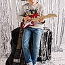 child, boy, hat, jeans, sweater, electric_guitar, black_guitar, amplifier, silver_streamers, barefoot, music, musician, studio, posing, indoor, portrait, young, focused, instrument, photography