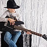 Sohann participe au concours pour gagner de l'argent avec cette photo : child, boy, guitar, electric_guitar, hat, fedora, music, musical_instrument, amplifier, streamers, silver, jeans, sweater, indoor, studio, pose, playing_guitar, young, casual, concentration