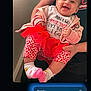 baby, child, smiling, person, indoor, pink_clothing, red_tutu, heart_pattern, socks, happy, holding, adult, tshirt, casual_clothing, portrait, cute, infant, joyful, family, baby_girl