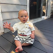 Sam is registered to the contest to win money with this photo: baby, child, outdoor, deck, wood, shirt, shorts, waving, expression, sunlight, shadow, house, window, door, plank, sitting, person, cute, summer, casual
