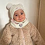 toddler, child, hat, pom_poms, knitwear, coat, beige, white, minnie_mouse, cute, smile, face, portrait, indoor, warm_clothing, button, standing, person, young_child, expression