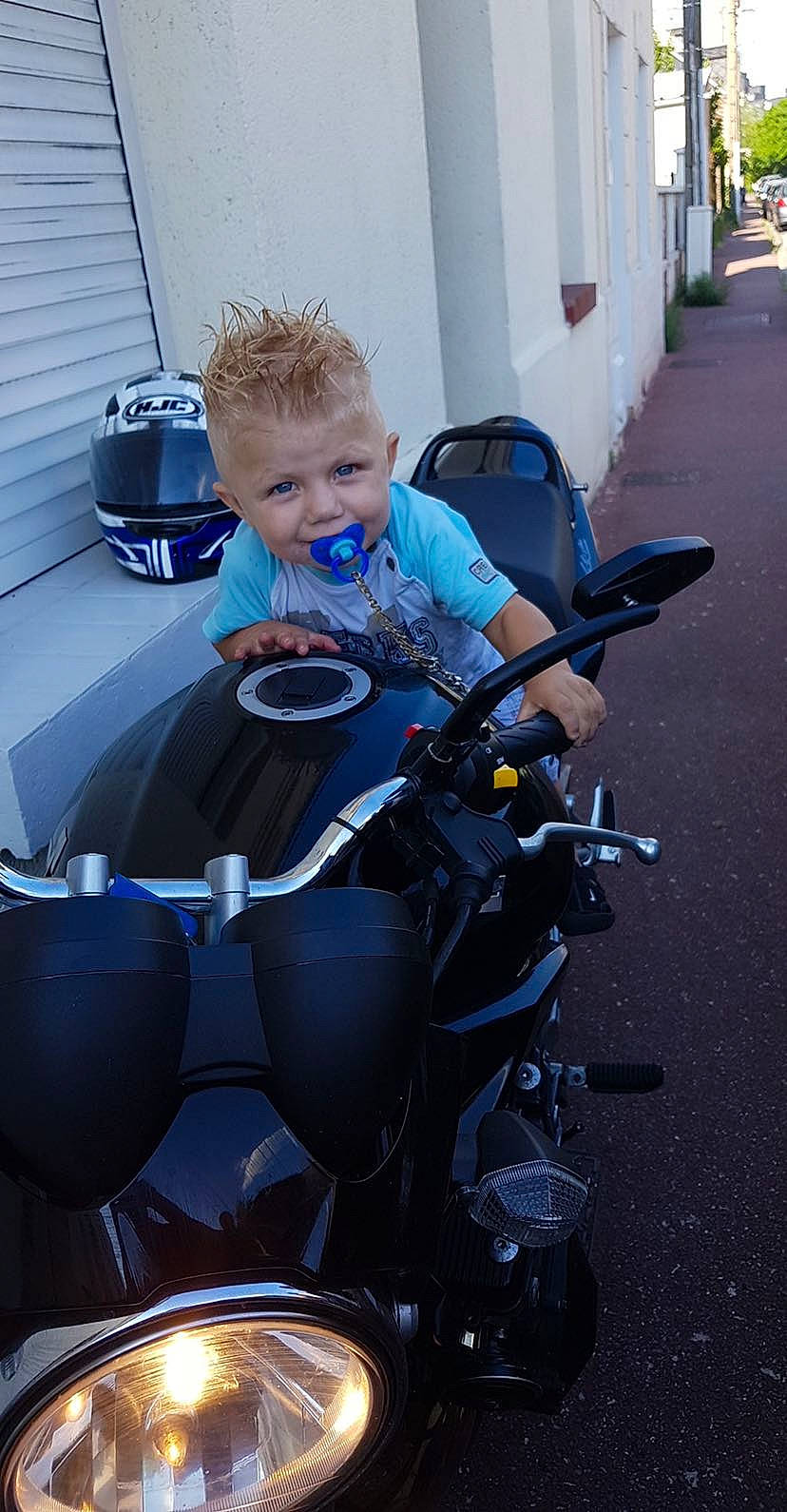 Alonzo participe au concours pour gagner de l'argent avec cette photo : automotive_window_part, electric_blue, glass, helmet, motorcycle, motorcycle_accessories, person, personal_protective_equipment, toddler, vehicle, wetsuit, window, windshield