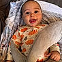 Nasir joined the competition — help win amazing prizes! baby, child, smiling, face, blanket, clothing, onesie, pumpkin_pattern, happy, indoors, cute, hand, soft, cozy, portrait, person, infant, expression, warm, comfort