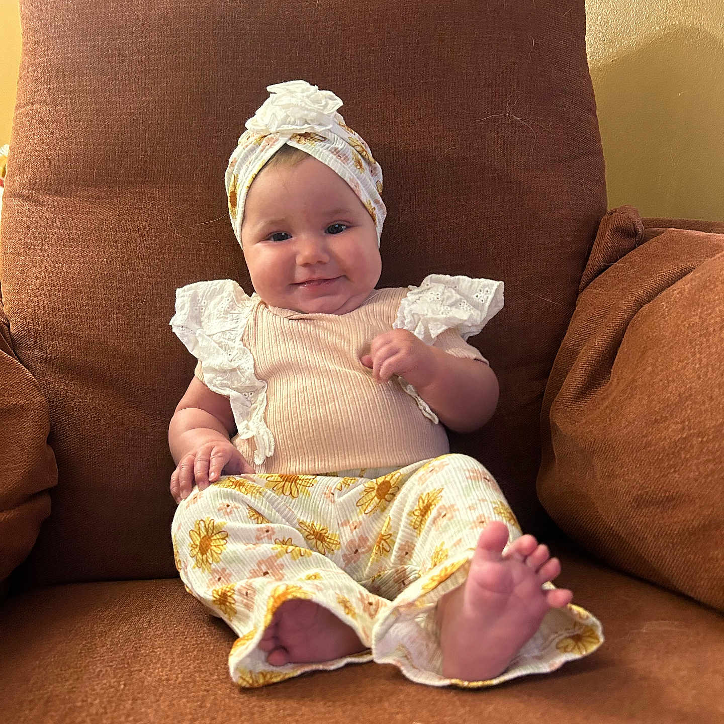 Rosealine is registered to the contest to win money with this photo: armchair, baby, baby_girl, brown, child, clothing, comfort, cozy, cute, feet, flower_pattern, happy, headwrap, indoors, infant, pants, person, portrait, sitting, smile