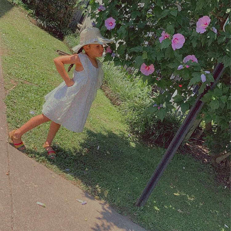 Nicole is registered to the contest to win money with this photo: annual_plant, dress, flower, grass, human_leg, lawn, leisure, magenta, people_in_nature, petal, plant, recreation, road_surface, rose, rose_family, shrub, sidewalk, toddler, tree, waist