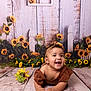 Ayla joined the competition — help win amazing prizes! baby, child, smiling, sunflower, headband, brown_clothing, wooden_floor, flower, flower_decoration, background, happy, portrait, indoors, crawling, cute, infant, nature_theme, yellow, green, plant