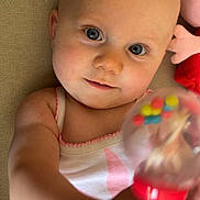 Khloé a rejoint le concours — aidez-le/la à gagner de superbes lots ! baby, infant, child, face, blue_eyes, rattle, toy, plush_toy, white_tank_top, pink_clothing, close_up, skin, arm, hand, lying_down, curious, indoors, soft_toy, playful, portrait