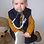 toddler, child, pacifier, vest, sweater, boots, rocking_horse, toy, plush_toy, teddy_bear, indoor, floor, wooden, person, face, blue_eyes, clothing, cute, baby, furniture