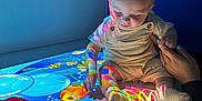 Daemon is registered to the contest to win money with this photo: baby, child, colorful, projection, underwater, fish, hand, light, shadow, indoor, table, person, sitting, clothing, sock, skin, adult_hand, curious, bright, pattern