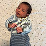 baby, infant, striped_clothing, blanket, stars_pattern, lying_down, cute, small_hands, face, head, newborn, cozy, soft_texture, sleepwear, child, portrait, indoors, resting, young, adorable