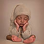 adorable, baby, child, close_up, cozy, cute, hands_on_cheeks, infant, knitted_hat, knitted_sweater, neutral_background, newborn, peaceful, portrait, resting, sleeping, soft_lighting, studio_photo, tiny_feet, warm_colors