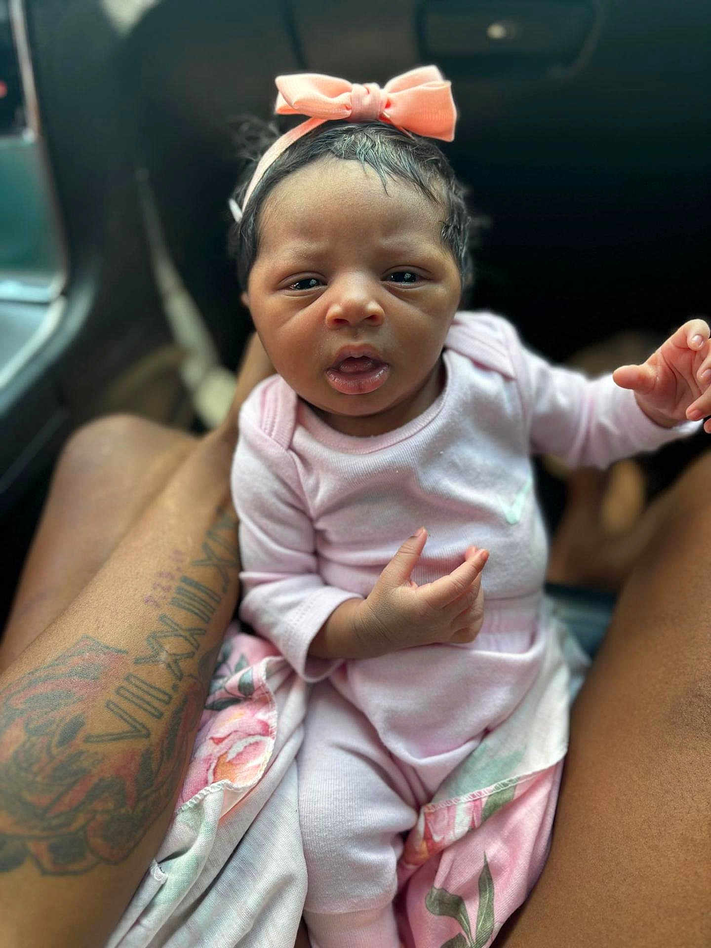 Caisleigh is registered to the contest to win money with this photo: baby, infant, pink_clothing, headband, bow, tattoo, legs, car_interior, blanket, person, cute, newborn, child, portrait, seated, hand, face, expression, soft_light, closeup