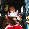 baby, brown_pants, canopy, car_seat, child, comfort, cute, footwear, indoors, infant, pacifier, person, plaid_shirt, plush_toy, portrait, red_shoes, seated, striped_fabric, warning_label, white_shirt