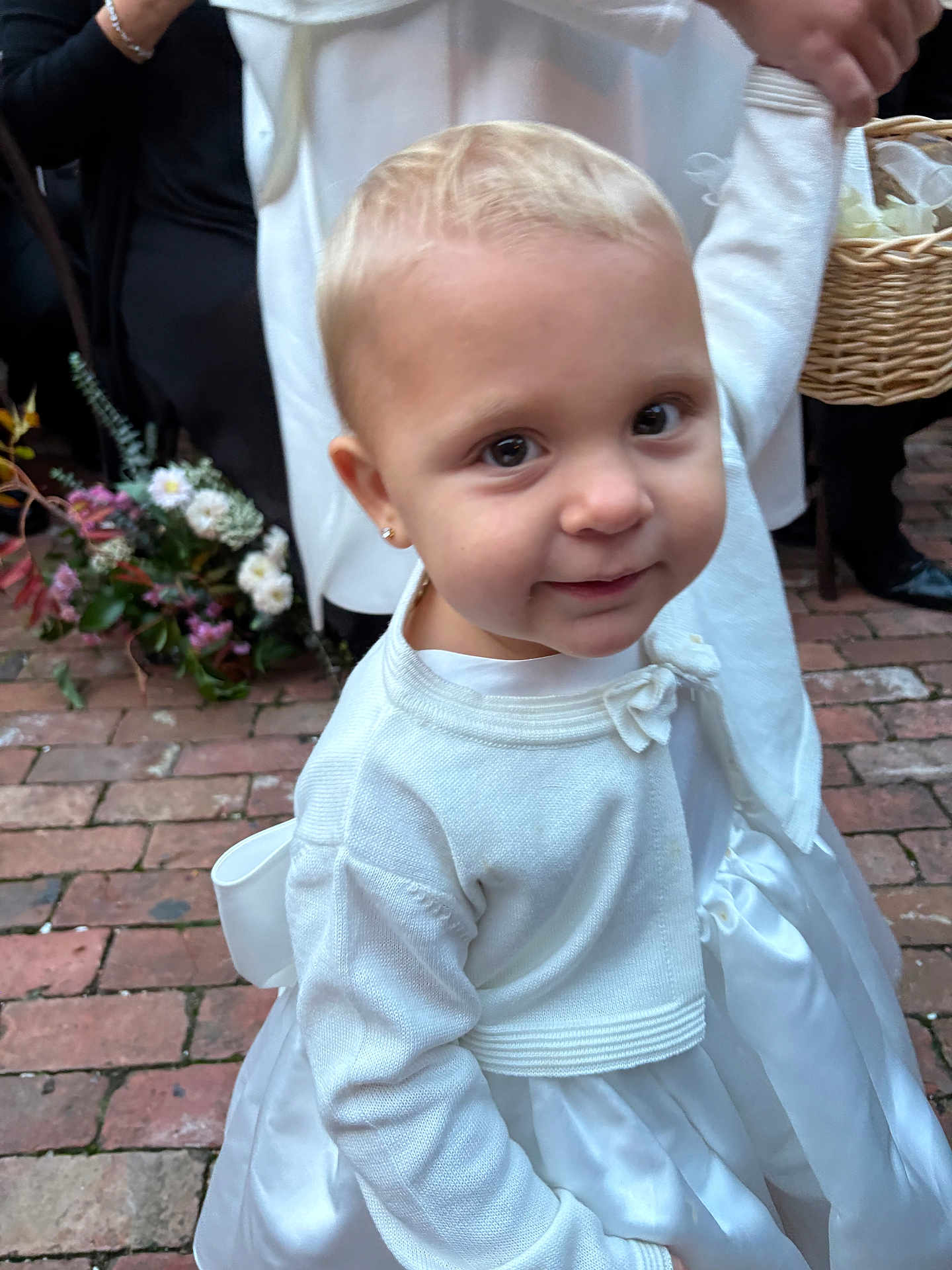 Addison joined the competition — help win amazing prizes! toddler, child, white_dress, cardigan, earrings, holding_hand, flower_arrangement, brick_floor, person, outdoor, formal_wear, cute, portrait, smiling, baby, young_child, event, people, hand, basket