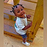 Romell is registered to the contest to win money with this photo: toddler, child, smiling, wooden_stairs, outdoor, playground, white_shirt, shorts, white_shoes, hair_twists, happy, cute, person, standing, looking_up, wood, railing, casual, daylight, floor