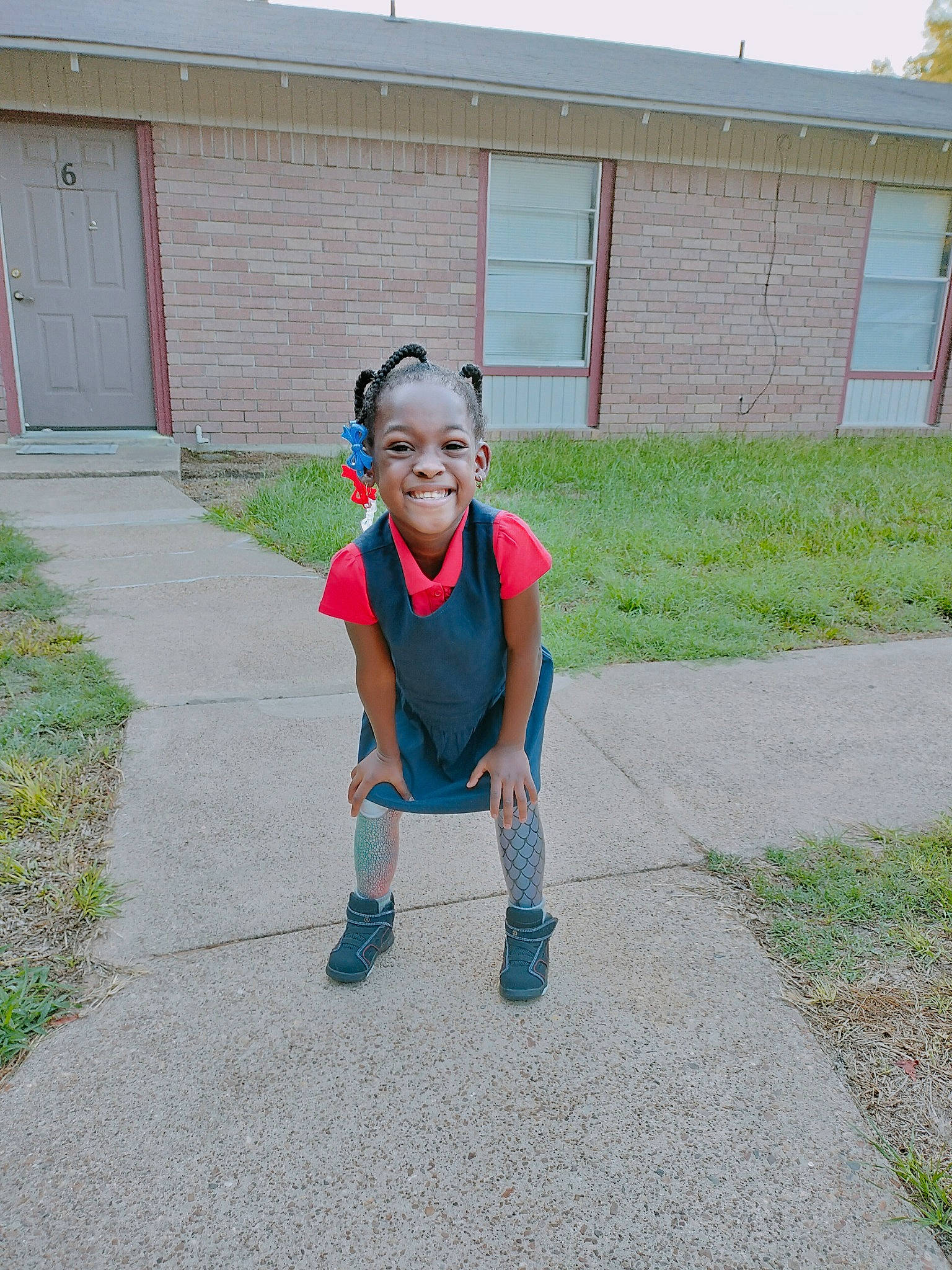 Rhyleigh is registered to the contest to win money with this photo: asphalt, concrete, denim, door, electric_blue, grass, hat, house, joy, leisure, person, plant, recreation, road, road_surface, shorts, sidewalk, smile, t_shirt, toddler