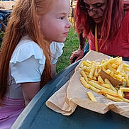 Joyce a rejoint le concours — aidez-le/la à gagner de superbes lots ! child, girl, woman, food, french_fries, table, outdoor, park, grass, trees, people, glasses, red_hair, white_clothing, pink_clothing, daylight, tent, event, nature, portrait