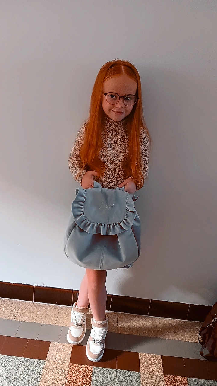 Joyce participe au concours pour gagner de l'argent avec cette photo : child, girl, red_hair, glasses, backpack, indoor, wall, floor, tiles, shoes, long_hair, standing, casual_clothing, smiling, fashion, young, person, portrait, cute, accessory