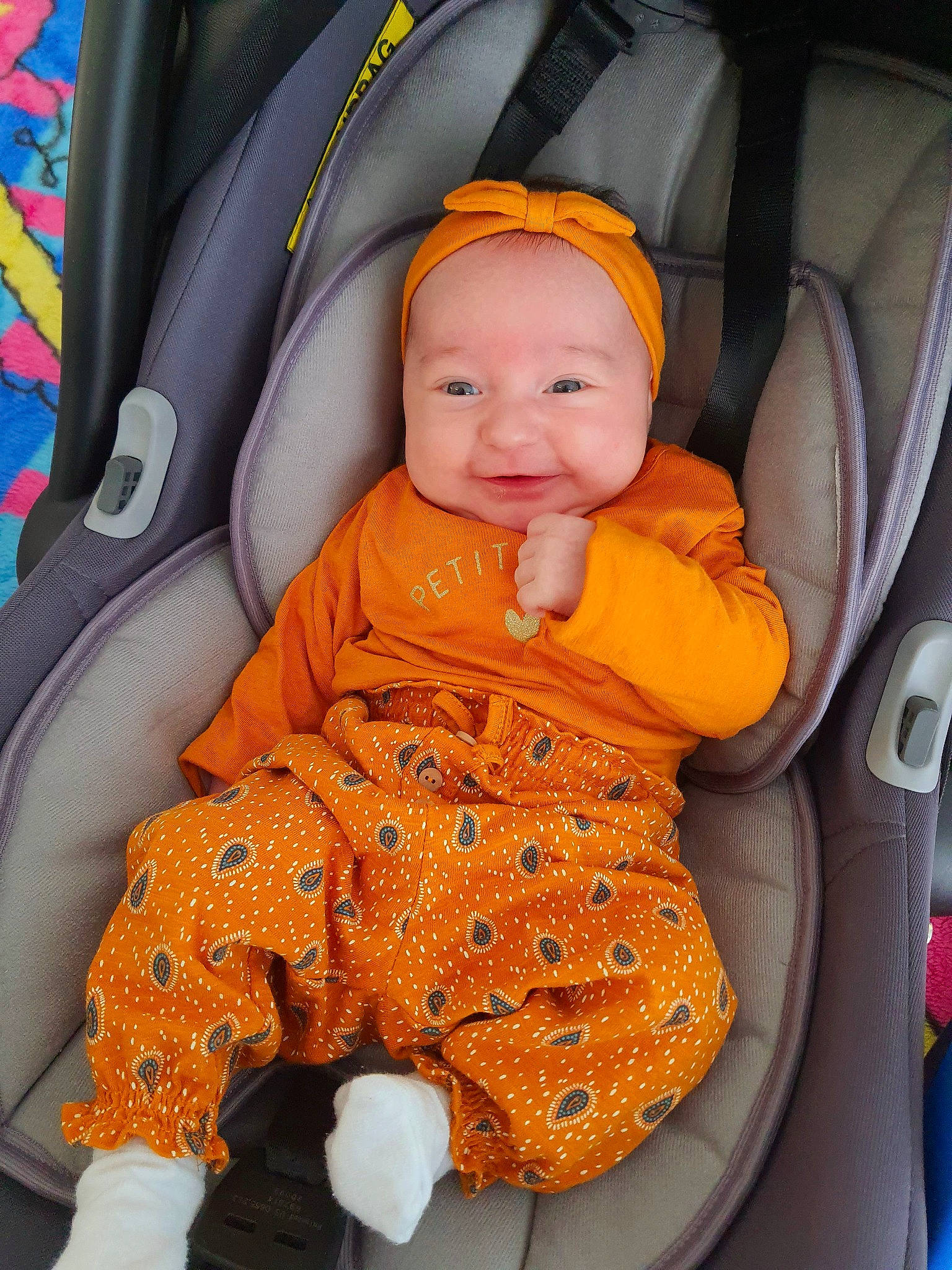 Mathilda a rejoint le concours — aidez-le/la à gagner de superbes lots ! auto_part, baby, baby_carriage, baby_in_car_seat, baby_products, baby_safety, baby_toddler_clothing, bag, black, car, car_seat, child, comfort, head, headwear, orange, person, product, smile, toddler